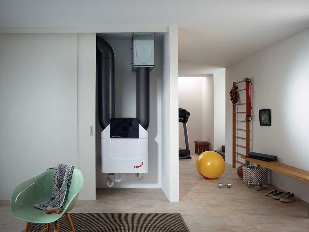 Wall-mounted Zehnder energy recovery ventilation unit with exposed ducting in a finished interior.